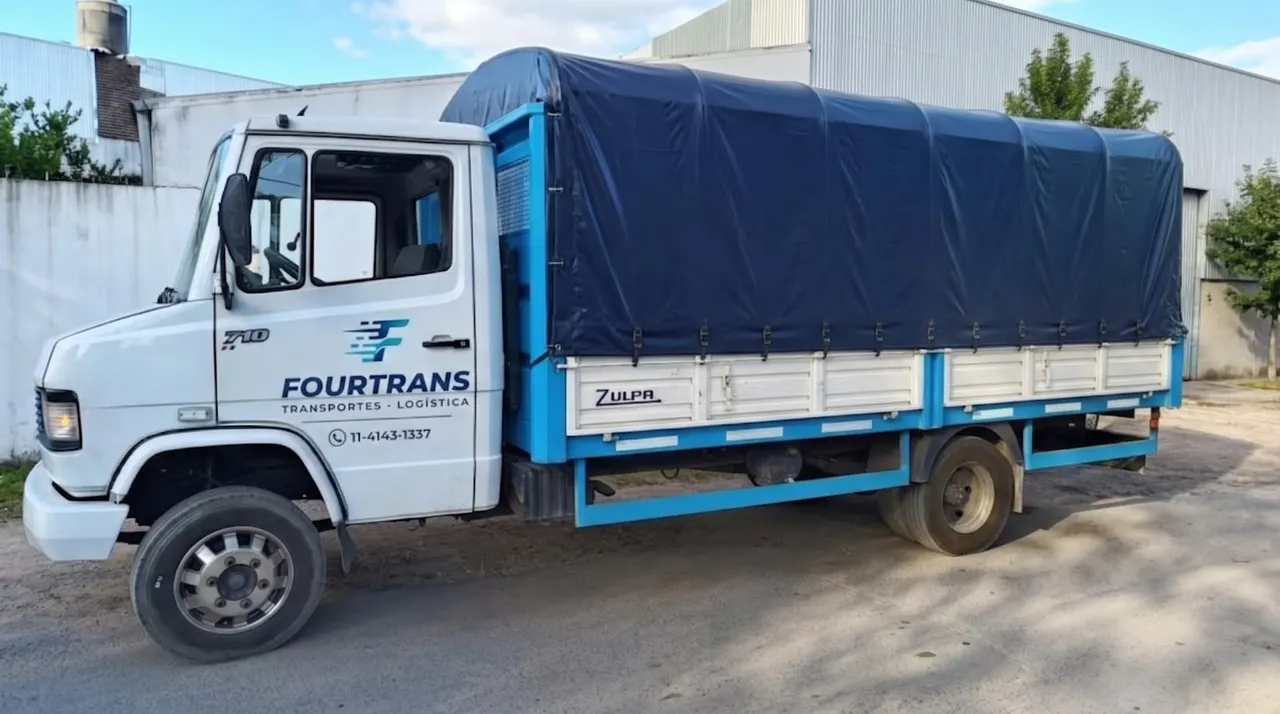 Camión Mercedes-Benz 710 de FOURTRANS de costado, con la caja techada con lona azul oscuro
